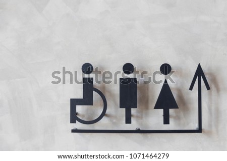 mens and womens disabled restroom signage with arrow made from steel plate on grey concrete wall.