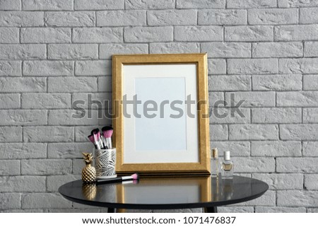 Mockup of blank frame and makeup brushes on table
