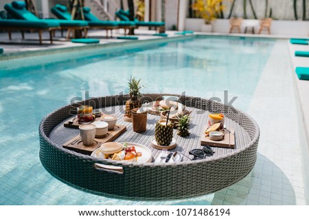 Picture of exotic lunch in hotel. Outdoor shot of table with fruits in swimming pool.