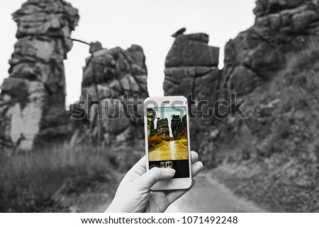 Amazing photo of a girl taking a picture of the famous rocky wall Externsteine in Germany, Horn Bad Meinberg