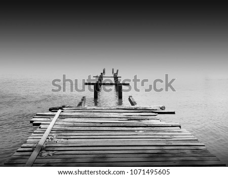Amazing old abandon wooden jetty in minimalist black and white fine art photography. (blurry soft focus noise grain visible full resolution) Nature composition