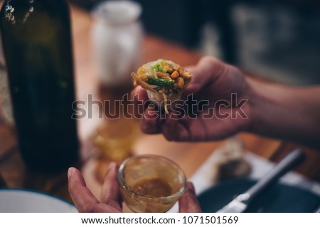 Young woman's hands eating healthy spring roll dipped in a creamy delicious sauce. Selective focus. Toned picture.