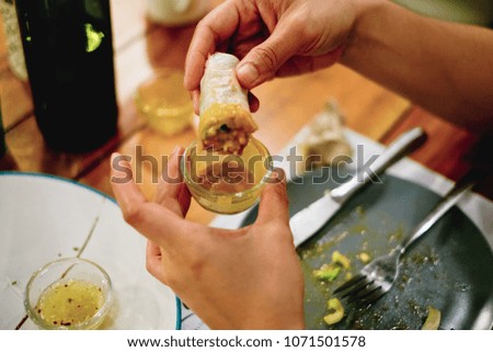 Young woman's hands eating healthy spring roll dipped in a creamy delicious sauce. Selective focus. Toned picture.