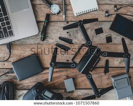top view of work space photographer with drone, battery, joystick controller, memory card, external harddisk, camera bag and camera accessory on wooden table background
