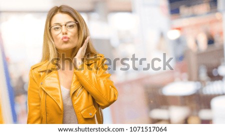 Beautiful young woman expressing love, blows kiss at camera, flirting at restaurant