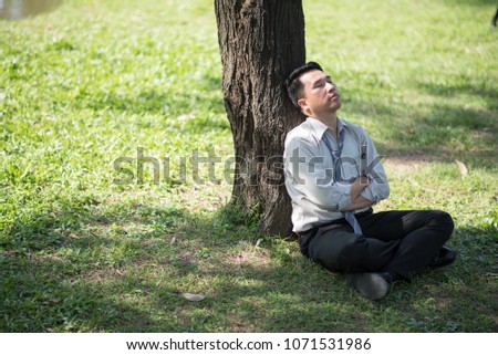 Business man failing and serious under tree in the park. He is stressed with work Unsuccessful disappointed in project