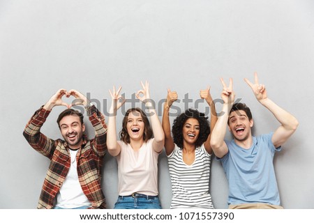 Photo of happy group of friends sitting isolated over grey wall background gesturing with hands.