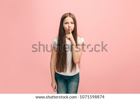 Secret, gossip concept. Young teen girl whispering a secret behind her hand isolated on trendy pink studio background. Young emotional girl. Human emotions, facial expression concept.