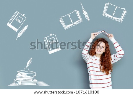 Amazing literature. Creative cheerful young writer feeling inspired while being surrounded with various books of different famous authors Royalty-Free Stock Photo #1071610100