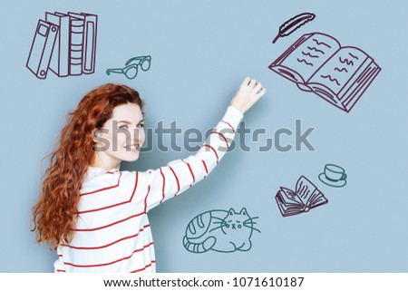 Talented author. Positive talented young writer looking happy while working at the new book Royalty-Free Stock Photo #1071610187