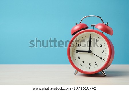 Red vintage alarm clocks on wooden table and light blue background wall Royalty-Free Stock Photo #1071610742