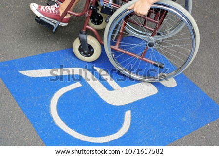 Woman in wheelchair suffers from mobility problems and stands on disabled parking space