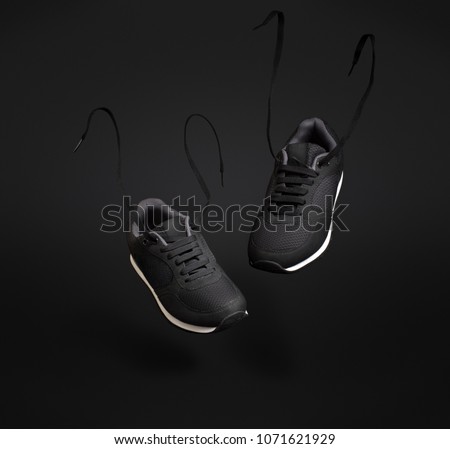 A pair of black unbranded sneakers floating in front of dark background. Royalty-Free Stock Photo #1071621929