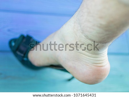 A man's leg in a woman's shoe with a heel. The concept of inappropriate shoe size, orientation disorders. Royalty-Free Stock Photo #1071645431