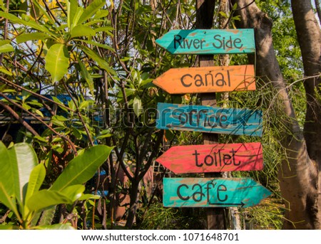 Old colorful wooden sign pointing the way, river side, canal, office,toilet ,cafe