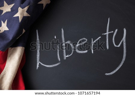 Liberty sign written on a chalkboard bordered by a vintage American flag