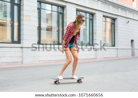 Beautiful young hipster woman with skateboard outdoors