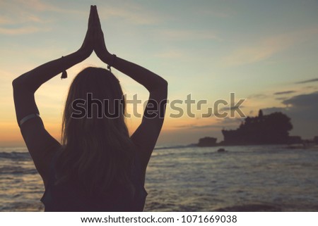 Young woman practicing yoga on the tropical beach.
