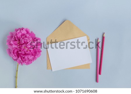 Mockup white greeting card and envelope with pink peony on a light blue background