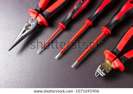 Tools electrician screwdrivers, pliers, platypuses on black background
