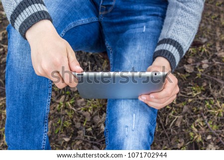Boy with  tablet in his hands sits on  grass. Preparation for  exam in nature