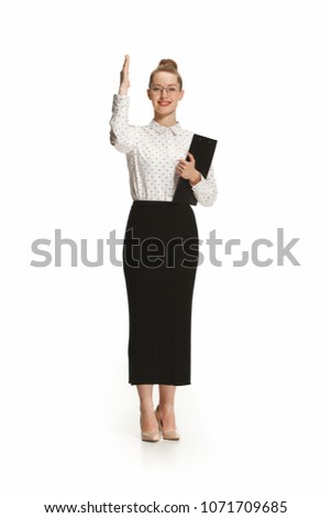 choose me. Full length portrait of female teacher holding a folder isolated against white background. Young caucasian woman with glasses standing at studio. School, college education concept