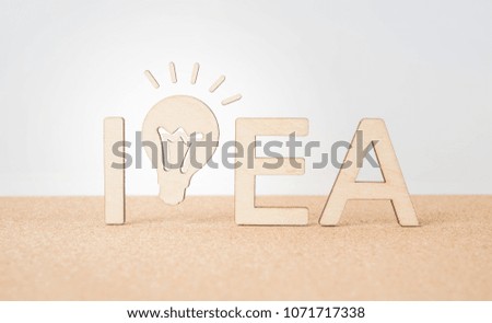 Business and design concept - wooden word " idea " and lightbulb on wooden desktop and white background 