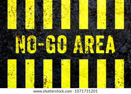 “No-Go Area” warning sign in yellow letters painted on grungy concrete wall with yellow stripes. Sign as concept for: do not enter the area, caution, danger or off limits in violent urban areas.