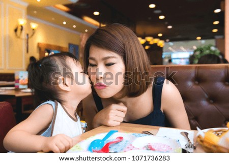Pretty young woman hugging cute girl in her arms at domestic room in the morning. Happy mother hugging and kissing her little daugther at home