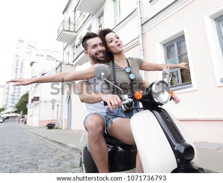 Beautiful young couple is smiling while riding a scooter