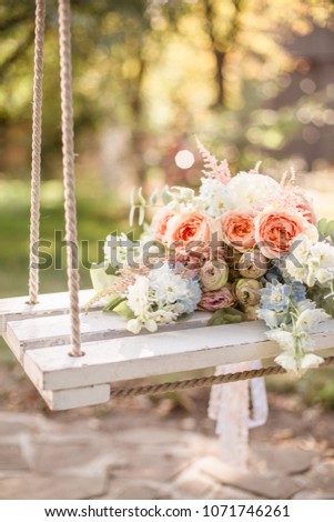 Wedding flowery bouquet of pastel flowers on a wooden swing Royalty-Free Stock Photo #1071746261