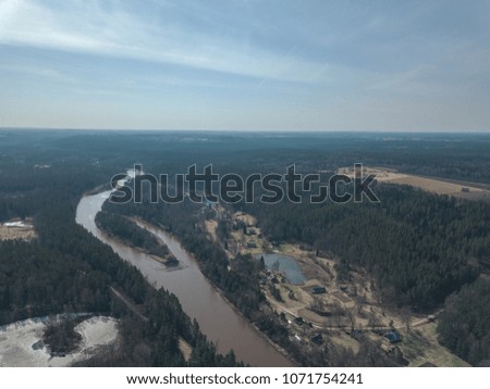 drone image. aerial view of frozen riverbank in spring forest, Gauja, Latvia - vintage film look