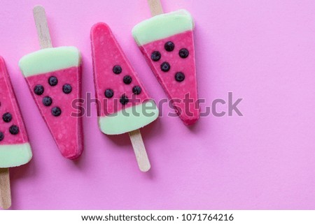 Watermelon shaped summer ice lolly on a pastel pink background