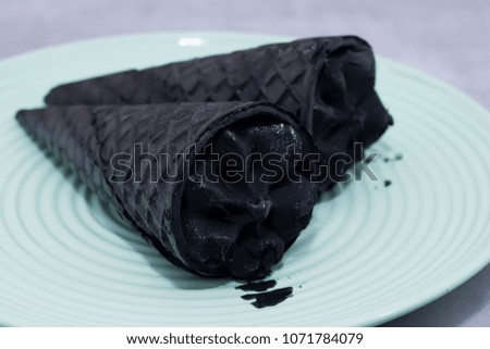 Trendy food. Black ice cream in traditional portioned black cones. Copy space. Soft focus.