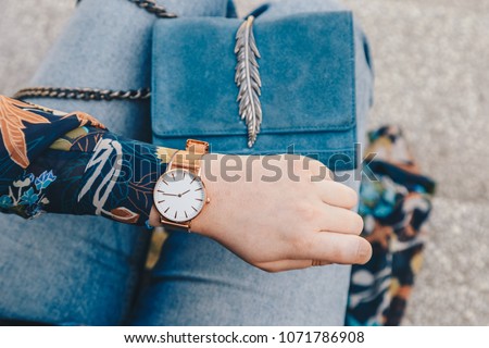 street style fashion details. close up, young fashion blogger wearing a floral jacker, and a white and golden analog wrist watch. checking the time, holding a beautiful suede leather purse.
 Royalty-Free Stock Photo #1071786908