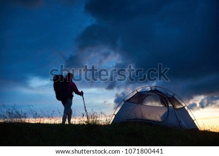 Shot of a backpacker standing near the tent on top of a mountain on sunset copyspace camping hiking campisite nature scenery evening landscape freedom achievement success leadership.