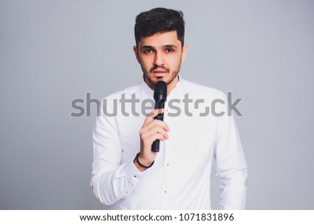 Showman interviewer with emotions. Young elegant man holding microphone against white background.Showman concept.
