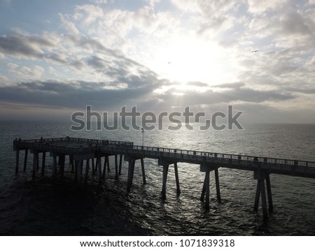 Drone picture of beach pier and sunset with birds