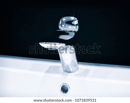 Luxury modern style faucet mixer on a white round sink in beautiful dark blue interior bathroom