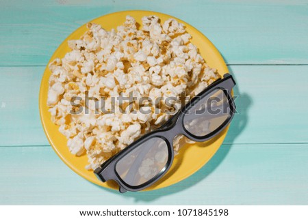 yellow plate full pop corn, on a plate glasses for viewing 3d films, concept cinema