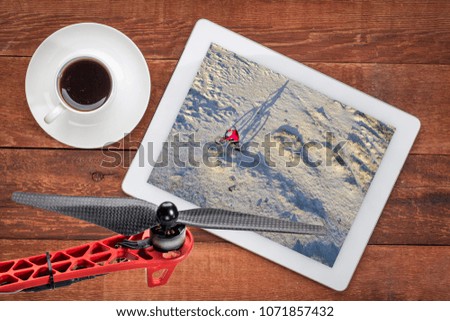 Riding a fat bike on a desert trail, reviewing an aerial image on a digital tablet with a cup of coffee