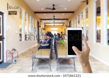 Woman use mobile phone, blur image of the parents sit and wait for the kids in front of the classroom as background.