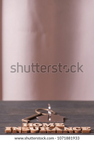Home Insurance text with house key on wooden table top.