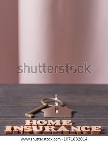 Home Insurance text with house key on wooden table top.