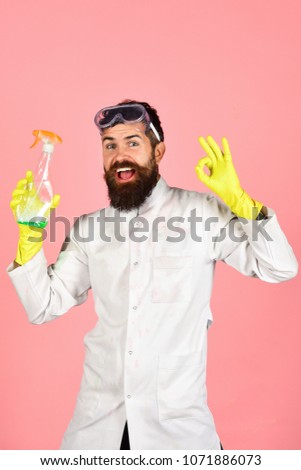 Cleaning, cleaning products. Victory over mud - happy man with beard and mustache in glasses in uniform and gloves holding cleanser spray and shows sign ok. Copy space for advertise cleaning service.