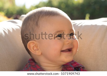 Happy white baby boy laughing during summer time. Beautiful natural light is giving a summer vibe with a yellow tones.