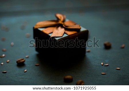Black surprise box. Brown bow. Surprice for darlin love. Blur dark studio background of black table. Professional photo session. Professional photo studio. Some coffee beans on black table