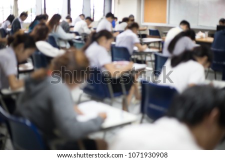 blur focus.back view abstract background of examination room with undergraduate students inside. university student in uniform sitting on lecture chair doing final exam or study in classroom.