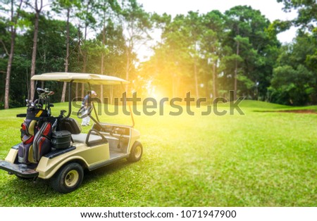 Soft club cart on golf course and golfer swing golf ball to hole. Beautiful fairway in forest on mountain of summer holiday. Equipment on club cart for player 