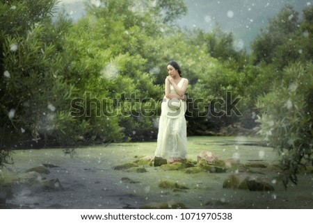 A woman with umbrellas in a snowy forest in the daytime.
